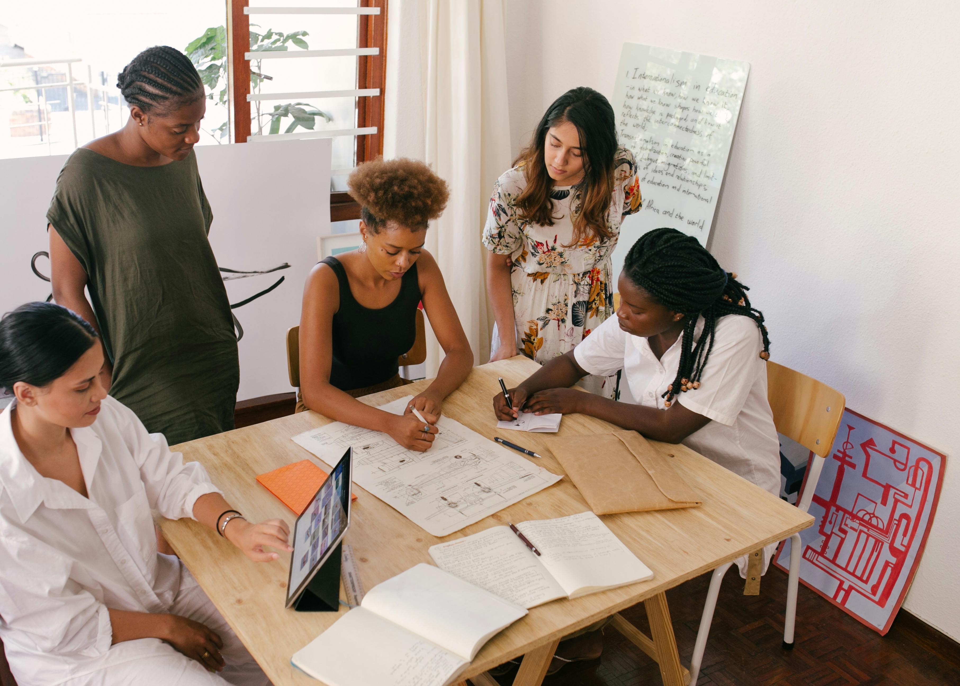 Image of a group of people in an office working around a shared desk with papers spread out over the surface