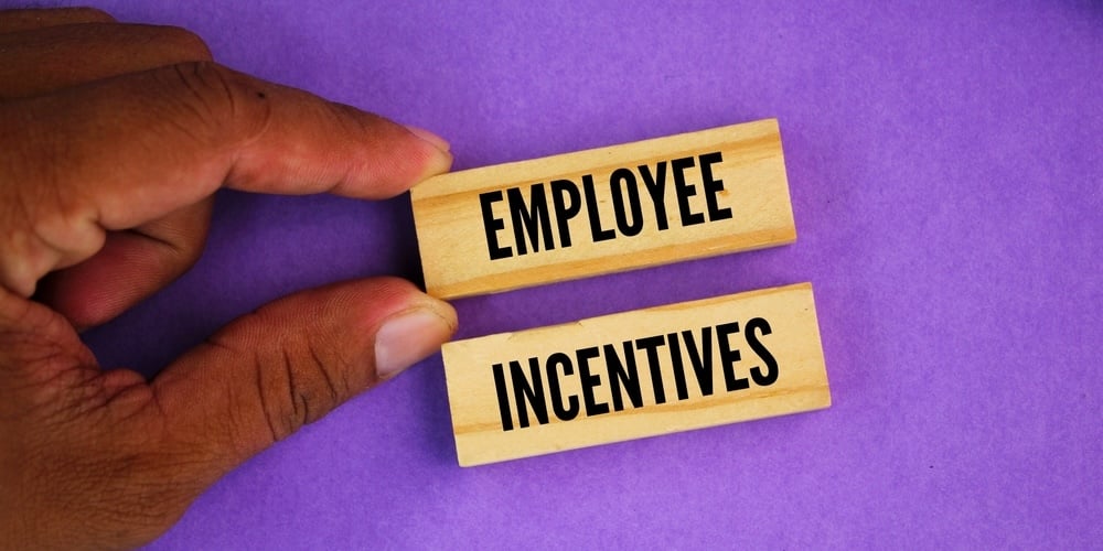 hand moving blocks that read Employee Incentives on a purple background
